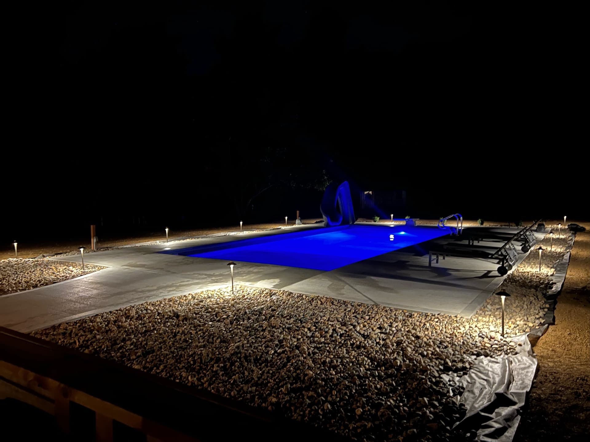 Pool deck with pathway lights and blue LED pool lighting at night